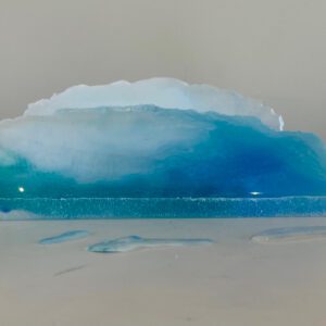 Available, July, 2025. A resin art piece resembling a cross-section of the ocean, with varying shades of blue, displayed on a white surface.